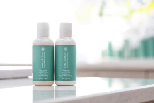Pureday To små flasker mærket "Rejsestørrelse Shampoo og Conditioner 70ml" på en badeværelsesdisk med sløret baggrund. Pureday To små flasker mærket "Rejsestørrelse Shampoo og Conditioner 70ml" på en badeværelsesdisk med sløret baggrund.