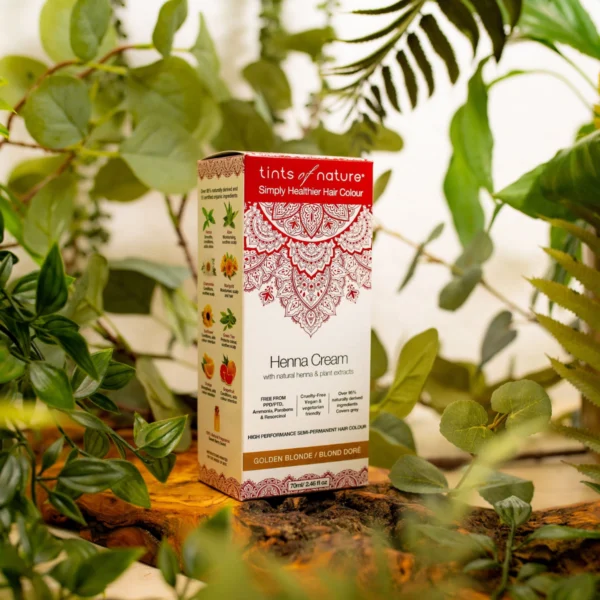 Pureday En æske Tints of Nature Henna Cream Golden Blond - 70 ml omgivet af frodige grønne planter på en træoverflade, der fremhæver dens økologi-venlige sammensætning.