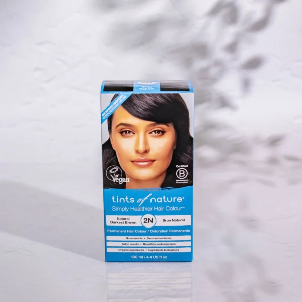 Pureday En æske med "Tints of Nature Dark Brown" vegansk hårfarve, med et billede af en kvinde med mørkt hår, placeret mod en blødt sløret baggrund.