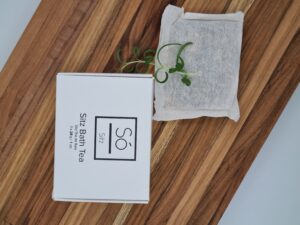 Pureday En æske mærket "Sitz Bath Tea til 3 siddebade" fra Pureday hviler på en træoverflade ved siden af en tepose og en kvist grønt, hvilket fremhæver dens organiske essens.